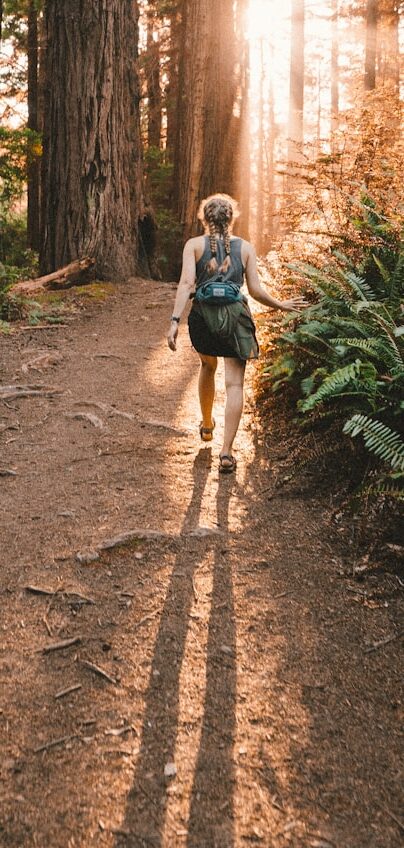 a woman walking down a path in the woods